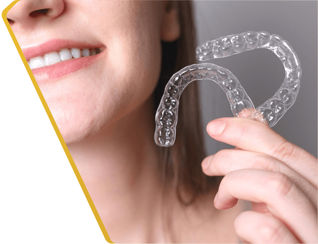 A patient holding a clear Invisalign<sup>&reg;</sup> aligner and smiling at Dentistry at Millennium Park in Chicago